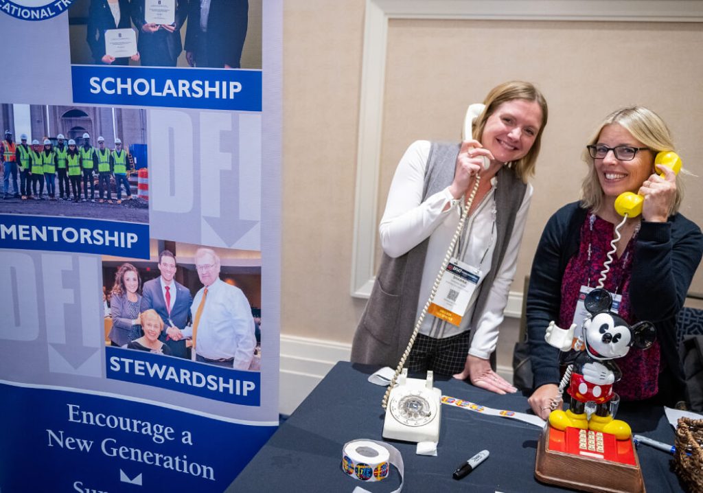 2 women holding corded phones to their ears.