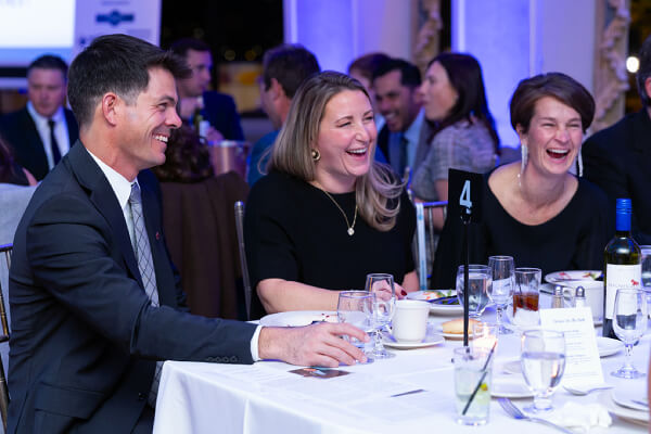 Adults in formal dress sitting at a dining table.
